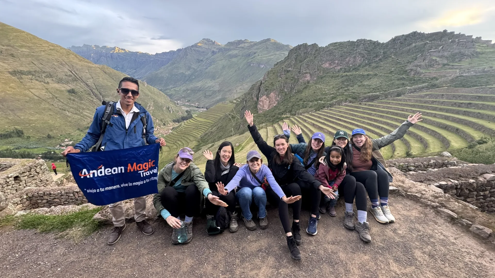 Group of travellers with the Andean Magic Travel flag on the Pisac terraces