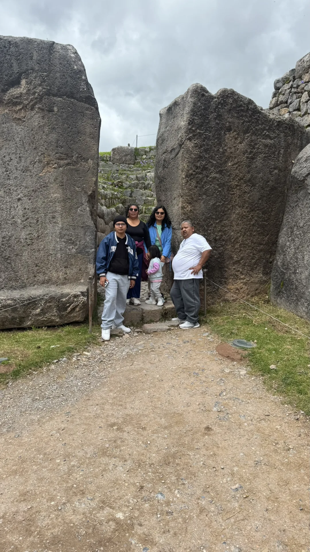 Familia entre las piedras gigantes de Sacsayhuamán, Cusco