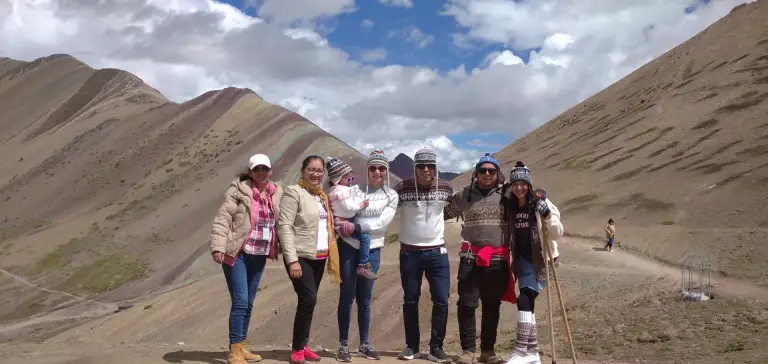 Group of travellers on the Rainbow Mountain trail, between coloured slopes