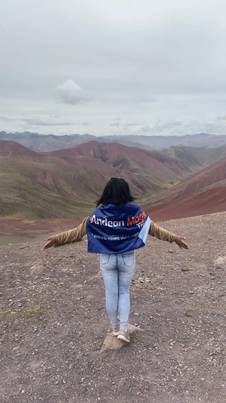 Viajera de espaldas con la bandera de Andean Magic Travel frente al Valle Rojo